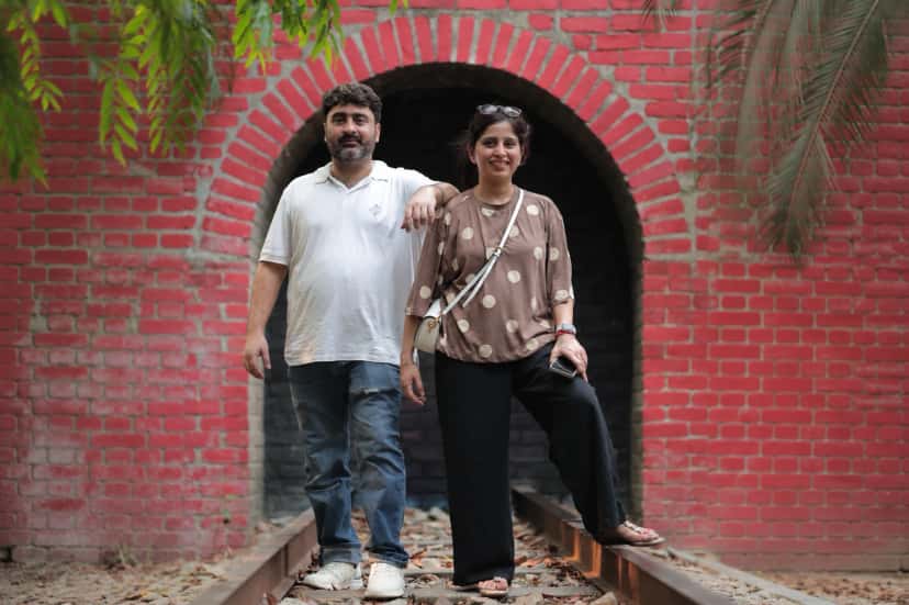 The founders of Anumya, a sister and brother, in front of a red brick arch